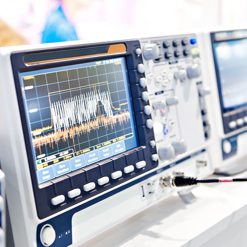 Nahaufnahme eines medizinischen Monitors, der eine detaillierte Wellenform mit Tasten und Knöpfen für Einstellungen anzeigt, in einer klinischen Umgebung.